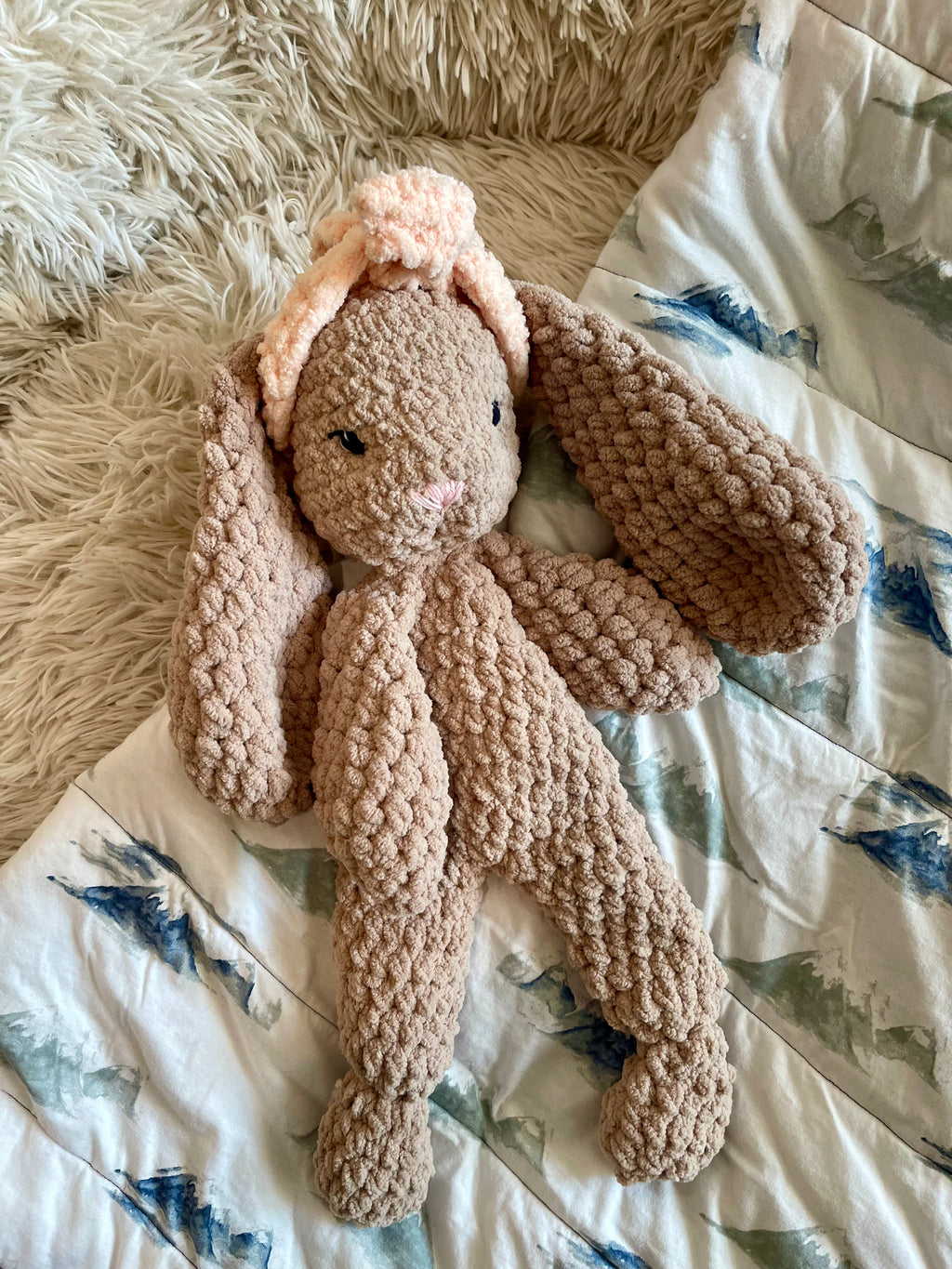 Crocheted bunny snuggler on patterned blanket